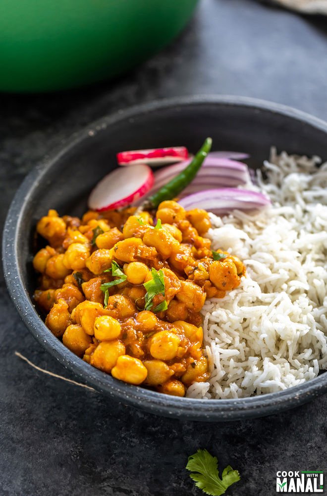 chana masala served with white basmati rice and sliced onions in a black color round bowl