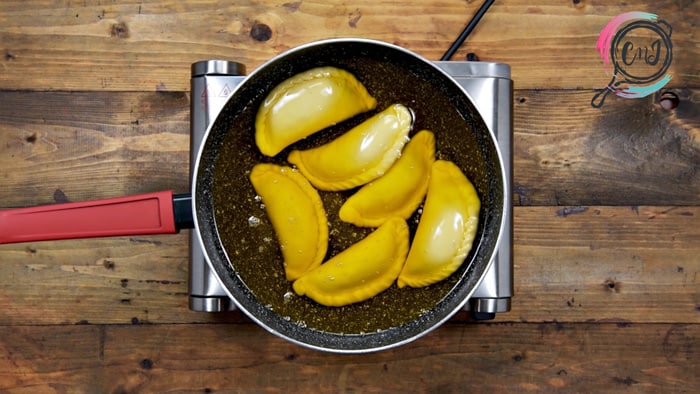 Gujia frying in ghee in pan.