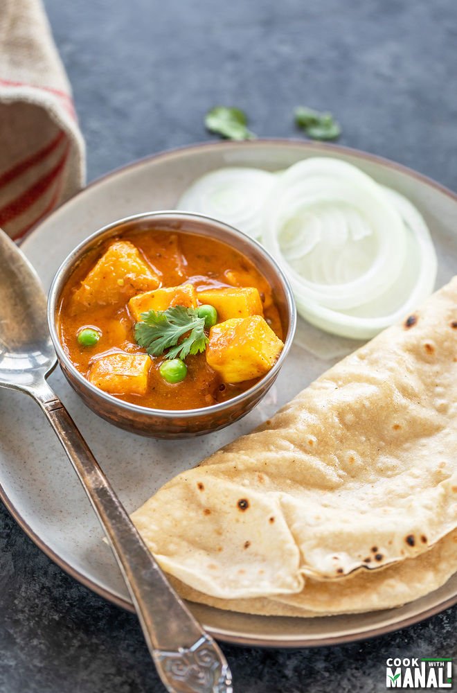 bowl of curry served with sliced onion and rotis in a plate