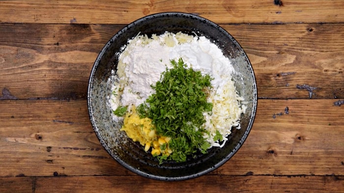 Cornflour, plain flour and chopped coriander leaves added in bowl.