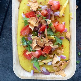 pureed moong dal topped with onion, tomatoes, cilantro, chilies and crushed papadum