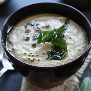 peanut chutney served in a wooden bowl with topping of curry leaves and mustard seeds